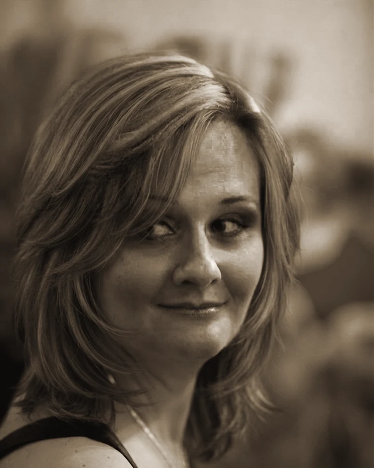 Retrato de Milena Ornelas, olhando para a câmera por sobre o ombro.